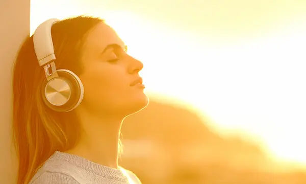 Mujer sintiendo la paz de la música relajante mientras disfruta del sol.