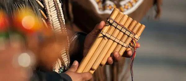 Primer plano de una zampoña en manos de un músico, parte esencial de la instrumental andina.