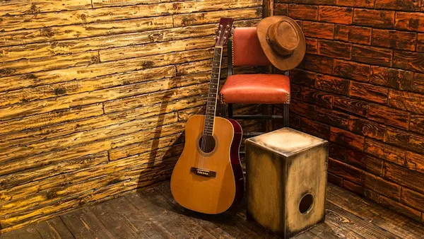 Rincón rústico con guitarra y cajón, elementos esenciales para crear música relajante.