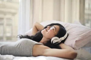 Mujer disfrutando de música relajante mientras descansa en su cama.
