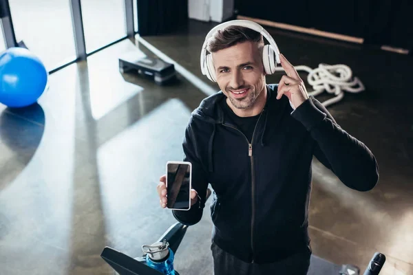 Hombre escuchando las mejores canciones para entrenar en el gym en sus audífonos