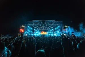 Escenario de concierto masivo con luces, sonido profesional y público asistente.